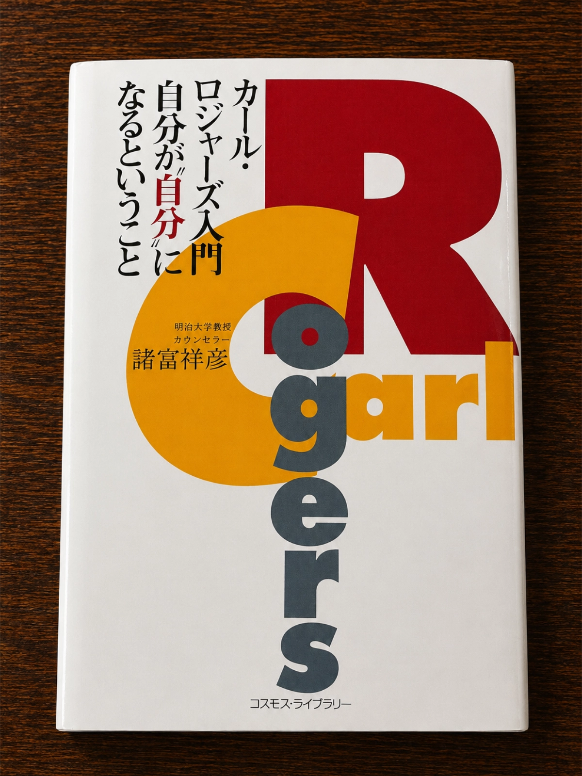 諸富祥彦著『カール・ロジャーズ入門 自分が自分になるということ』の本を木目の上に置いて撮影した写真